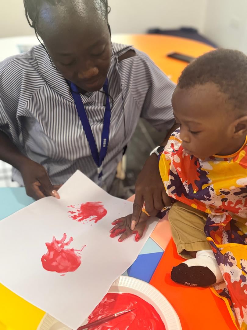 Teacher guiding a young child through a handprint activity